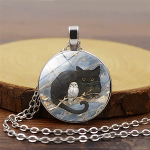 Close-up of glass pendant necklace featuring cat and owl illustration on wood
