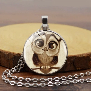 Detailed view of owl time gem pendant with cartoon illustration on dark wood background