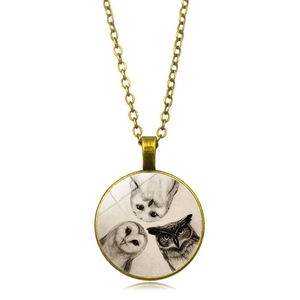 Detailed view of vintage bronze owl necklace pendant with three owl art prints under glass