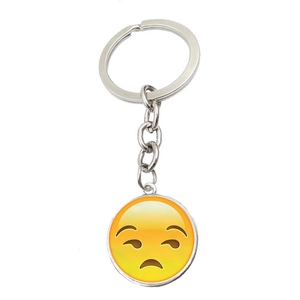 Detailed view of a round metal keychain with a yellow sad emoji under a glass cabochon