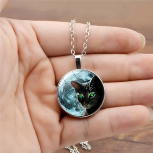 Silberne Halskette mit rundem Anhänger und schwarzer Katze mit grünen Augen im Zeitjuwel