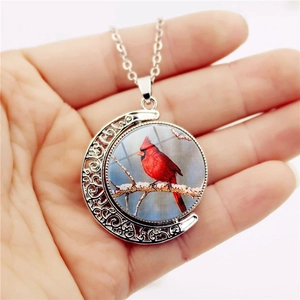 Rotating crescent moon necklace featuring a red cardinal bird pendant on silver alloy