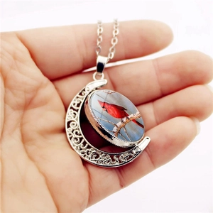 Macro shot of double-sided rotating crescent moon pendant with red cardinal bird design