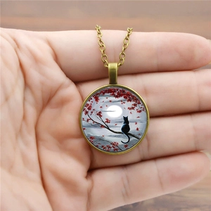 Detail of vintage cat pendant necklace with moon and red maple leaf art on copper