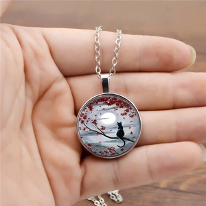 Vintage black cat and red maple pendant necklace with glass moon design held in hand
