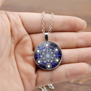 Handheld silver mandala necklace with sacred geometry sacred cube and starry background