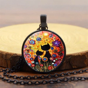 Detail of a black cat art pendant necklace featuring folk-style flowers and sun on wood
