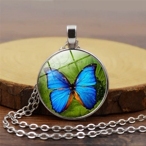 Detail showing a silver butterfly glass cabochon pendant on a wooden base