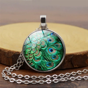 Detailed view of peacock feather glass pendant on a natural wood slice background