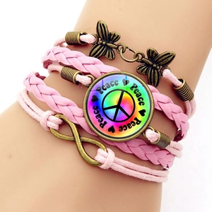 Detailed close-up of handmade pink woven multi-layer bracelet with peace sign and butterfly