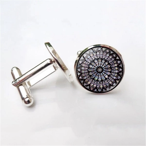 Detail of silver cufflinks featuring a colorful Gothic rose window pattern on a white base