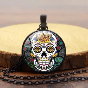 Detail of Mexico sugar skull glass cabochon pendant on a rustic wooden background