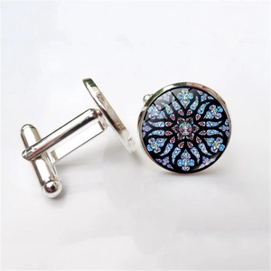 Macro view of silver cufflinks featuring colorful stained glass rose window patterns