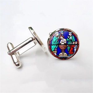 Macro view of silver-tone cufflinks featuring religious stained glass window art inserts