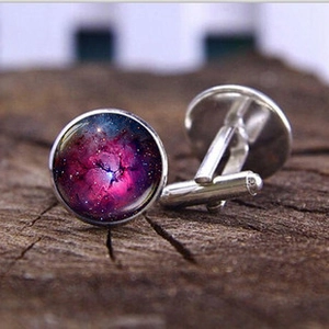 Detailed close-up of galaxy-themed glass cufflinks with silver metal finish on wood
