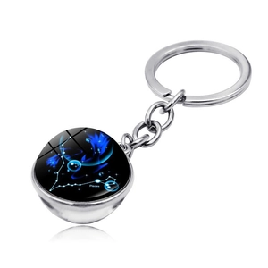 Detailed macro of the silver Pisces zodiac keychain with a glowing blue crystal ball pendant