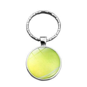 Detail view of a metallic tennis ball keychain with vibrant yellow texture and glass dome