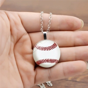 Detail of silver baseball pendant necklace held by hand over a dark wooden background