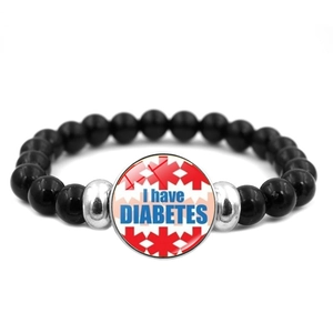 Macro detail of diabetes medical alert bracelet with black beads and glass dome pendant