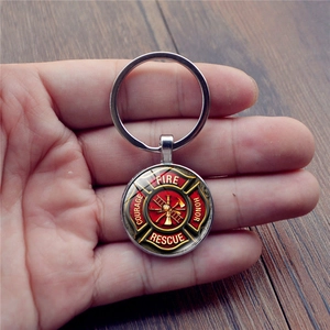 Silver firefighter keychain with glass cabochon fire rescue badge held in hand