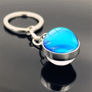 Macro shot of silver metal keychain featuring a double-sided blue galaxy glass ball pendant