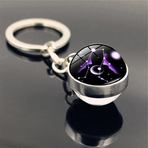 Macro view of Gemini zodiac keychain featuring silver metal and a glowing glass sphere