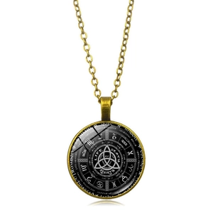 Macro shot of bronze Celtic Triquetra pendant with astrology signs and glass cabochon