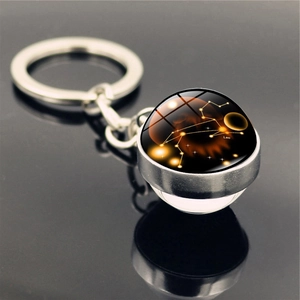 Close-up of double-sided glass orb keychain featuring Leo constellation on black background