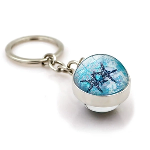 Silver metal keychain with a crystal glass dome pendant featuring two blue starfishes