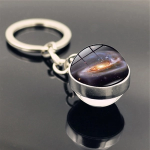 Macro view of solar system galaxy nebula double-sided glass ball keychain on black surface