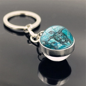 Detailed macro view of sea turtle art inside crystal ball metal keychain with ocean blue tones