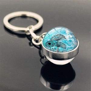 Close-up of silver keychain with double-sided glass pendant featuring blue floral art
