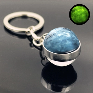 Macro shot of luminous Neptune planet glass dome keychain with green glow effect details