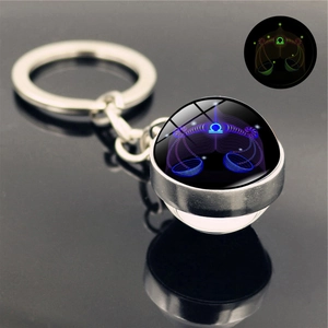 Detailed view of glowing Libra zodiac keychain with crystal ball on reflective black surface