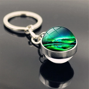 Close-up of Northern Lights glass ball keychain with starry aurora patterns on reflective surface