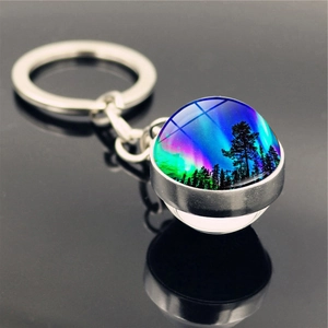 Macro detail of aurora borealis glass ball keychain with forest silhouette and silver base