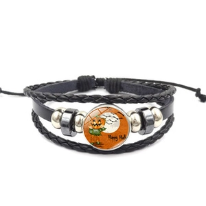 Detail of multi-layer leather bracelet featuring a Halloween pumpkin glass dome charm