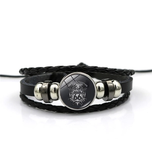 Detail of multi-layer black leather bracelet with vintage Route 66 glass cabochon charm