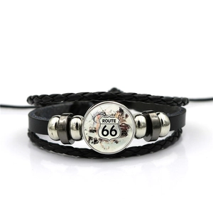 Detailed macro view of black leather bracelet featuring the vintage Route 66 glass dome charm