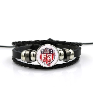 Detail of multi-layer braided leather bracelet featuring New York Route 66 glass charm
