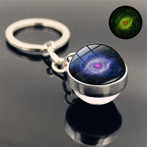 Glow in the dark galaxy glass ball keychain showing nebula pattern and green luminescence