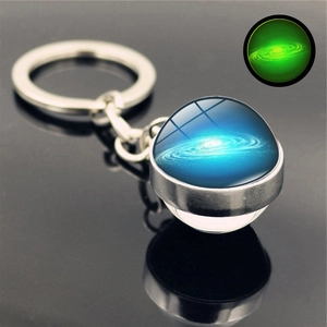Close-up of glowing galaxy glass pendant showing green luminous effect in the dark
