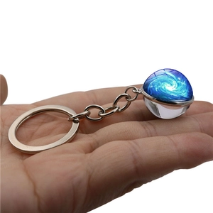 Cosmic galaxy swirl glass ball keychain with silver metal ring held in hand