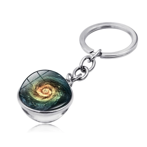 Macro shot of glass dome keychain showing colorful spiral galaxy and polished metal finish