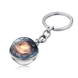Macro detail of universe galaxy glass ball keychain with swirling blue space nebula pattern