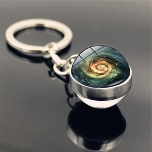 Detailed close-up of a double-sided glass galaxy pendant keychain with a blue spiral nebula