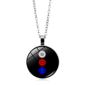 Close-up of a circular pendant necklace featuring sacred Sanskrit symbols in three colors