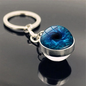Detail of a cosmic space nebula keychain with blue vortex pattern and glass ball pendant