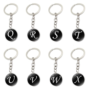 Détail de porte-clés alphabet avec pendentifs ronds noirs et lettres blanches cursives