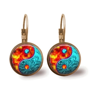Detailed macro view of bronze yin yang mandala lever-back earrings with fire and nebula patterns